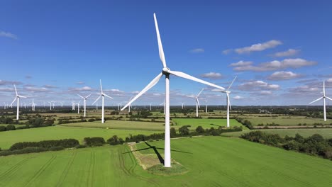 wind turbines farming wind energy, green fields, blue sky, countryside, sunny, slow drone orbit, green sustainable power