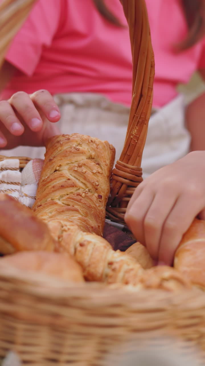 primer plano de una familia sentada al aire libre recogiendo pasteles frescos de una canasta de picnic, un niño con camisa verde se come rápidamente su elección mientras otros eligen sus golosinas, un momento de picnic acogedor