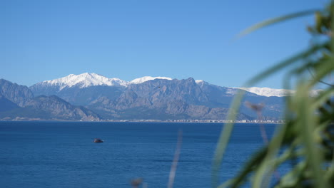 一艘土耳其船穿越地中海, 绿色的树叶和雪覆盖的山脉可见