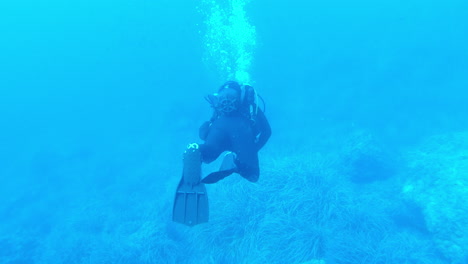 A-scuba-diver-swiming-near-the-sea-floor-on-a-dive-at-Mallorca,-Spain