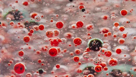 macro-shot-of-small-red-bubbles-floating-in-water-and-dark-bubbles-falling-to-ground-out-of-focus