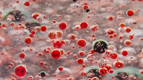 toma macro de pequeñas burbujas rojas flotando en el agua y burbujas oscuras cayendo al suelo fuera de foco