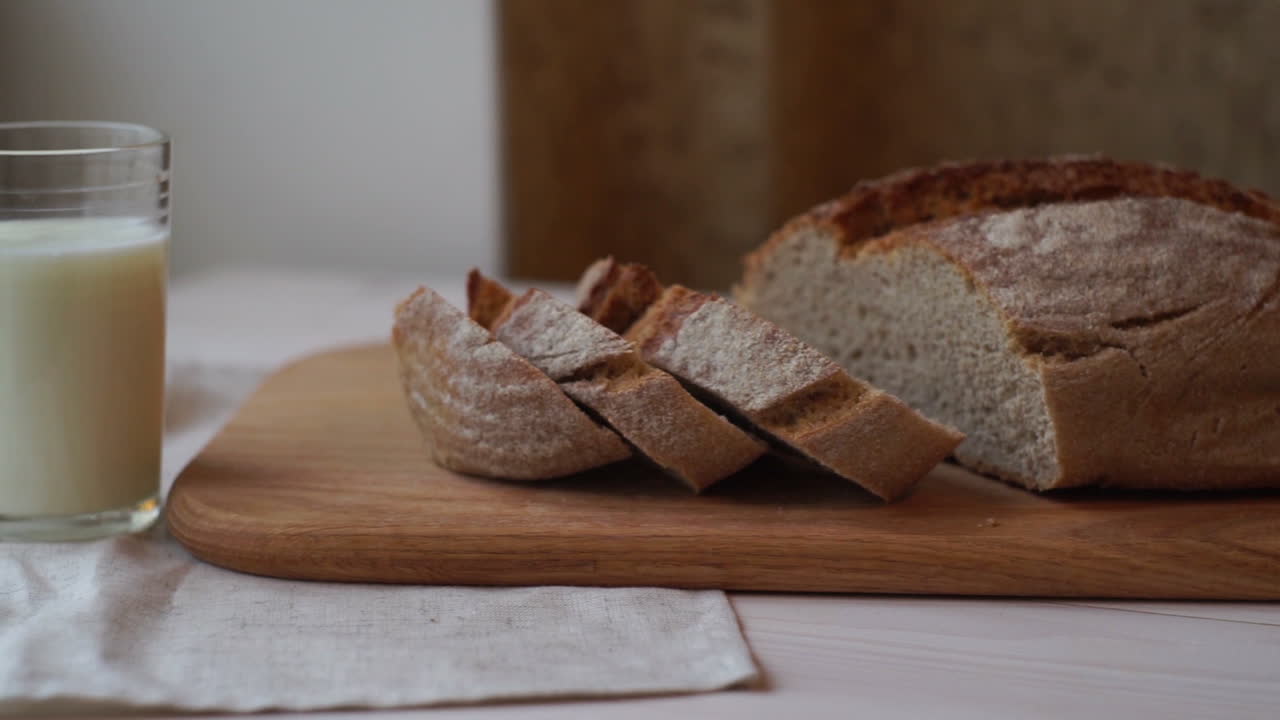 Slice bread on cutting board. Baked product. Milk glass on table. Bakery food