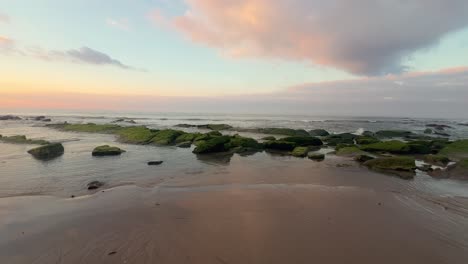 Walking-along-an-idyllic-beach-with-low-water-exposed-rocks-on-a-calm-afternoon