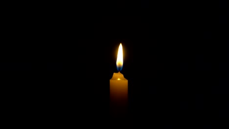 a single white candle burning. looping for use as a background or illustration of remembrance or celebration. the wind tries to put out the flame, but it recovers each time. the eternal flame.
