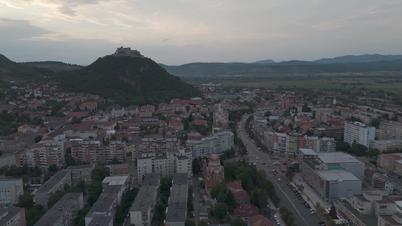 Aerial drone footage of Deva cityscape, highlighting the church in the foreground and the historic hilltop castle in the background