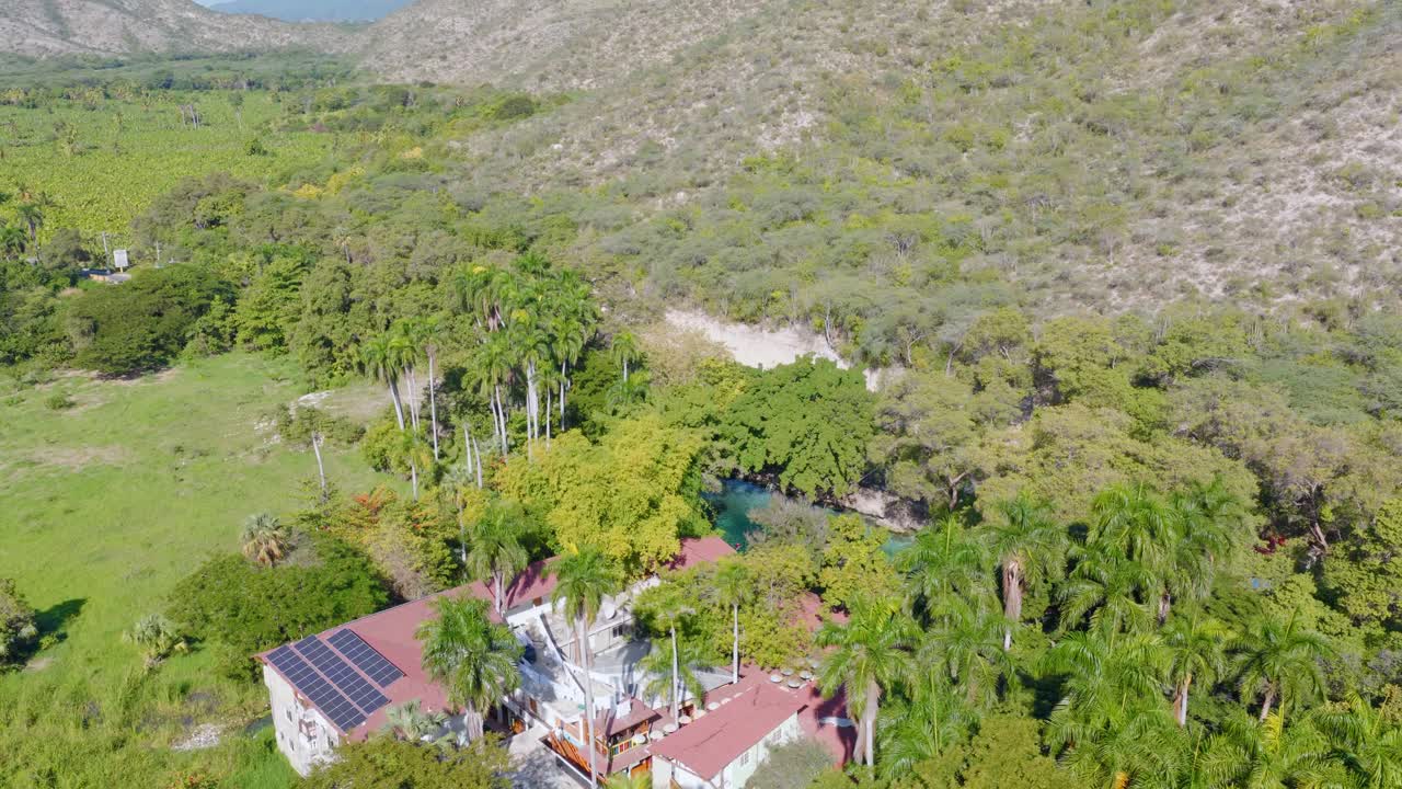 Vista aérea de propriedade com energia solar perto de Las Marías, Neyba, República Dominicana, cercada por exuberante floresta tropical e palmeiras. Energia sustentável em paisagem caribenha remota
