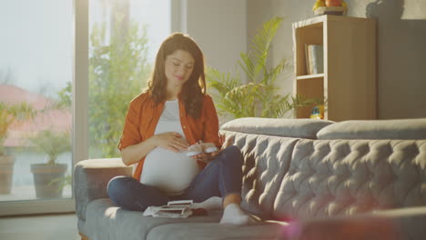 pregnant woman looking at baby shoes