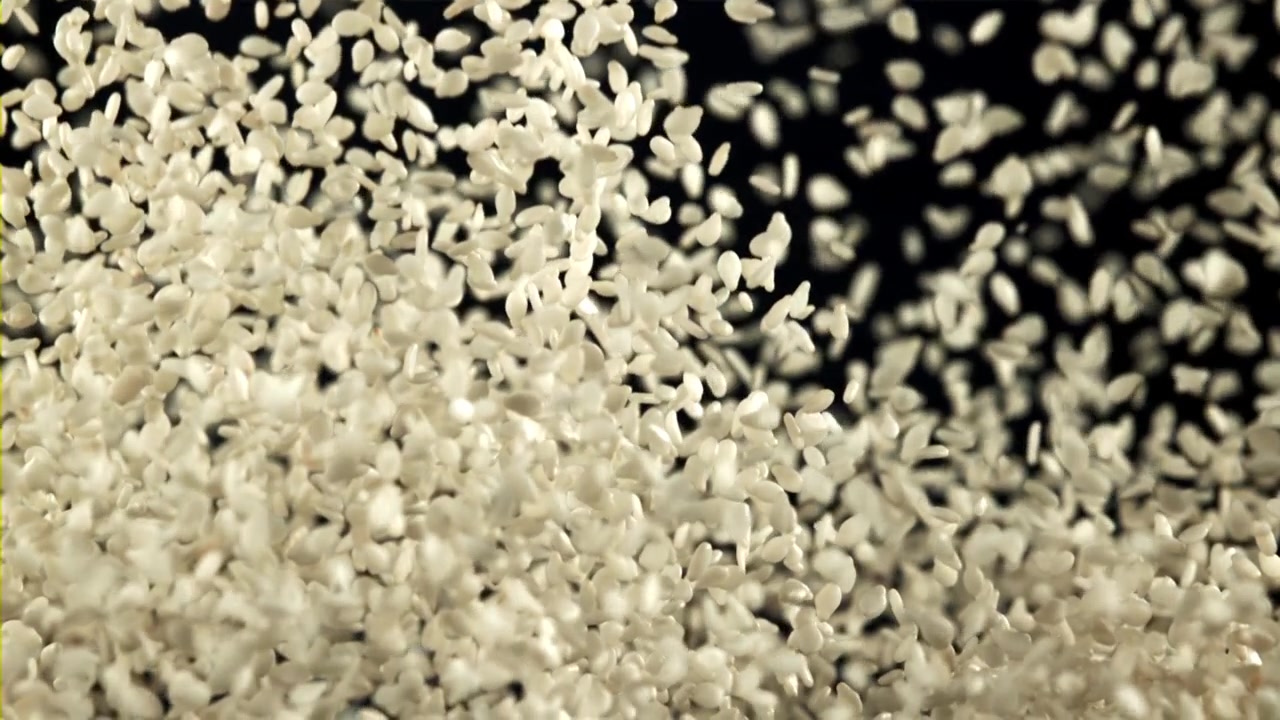 White Rice Grains Falling in Slow Motion Against a Black Background