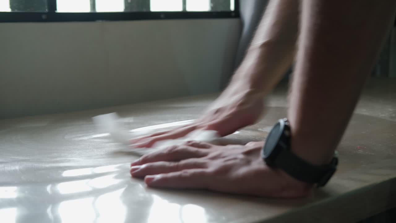Man Cleaning And Wiping Table With Plastic Cover In The Apartment. - closeup shot