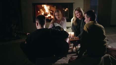 friends gather around fireplace playing guitar