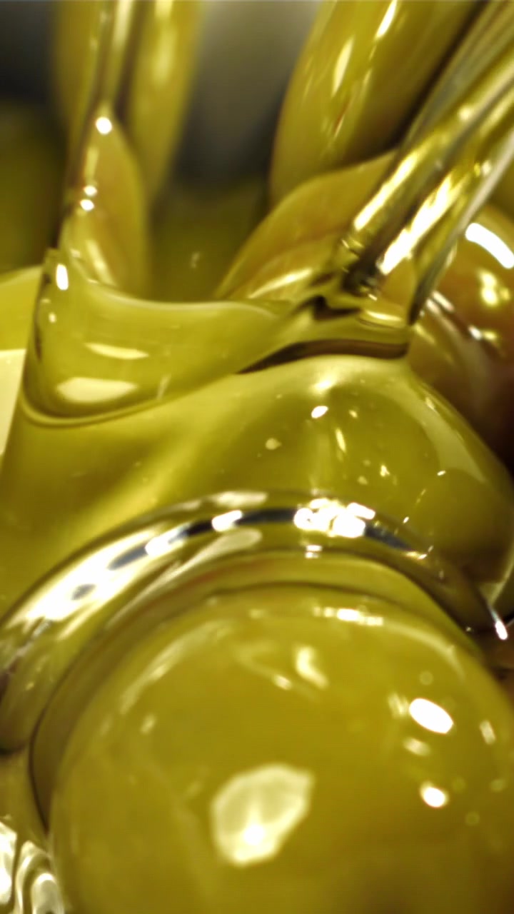 Olio d'oliva versato su olive verdi fresche in primo piano.
