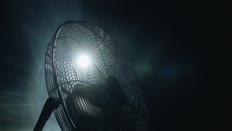 fan blades rotate in rays of light and fog