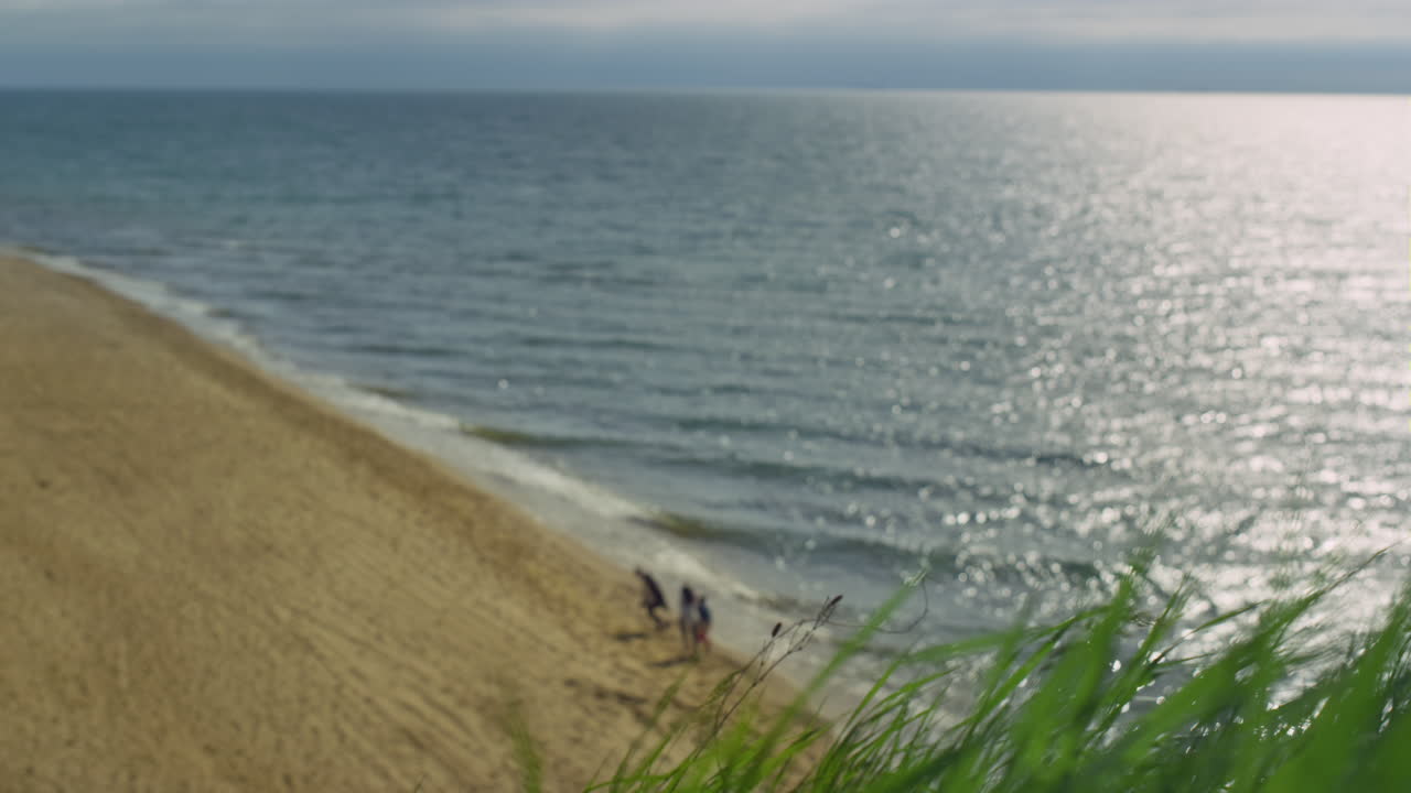 사람들은 바다 풍경과 모래 해변을 즐기고 있습니다. 바다 파도가 바 ⁇ 에서 폭발하고 있습니다.