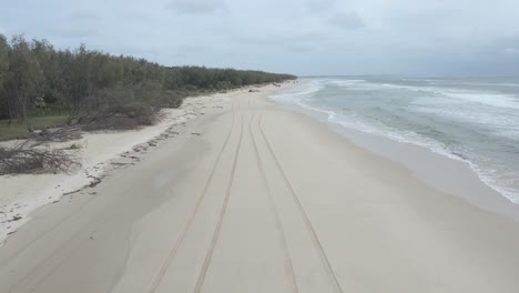a woman wearing swimsuit walking on sandy shoreline in north stradbroke island, moreton bay, queensland, australia