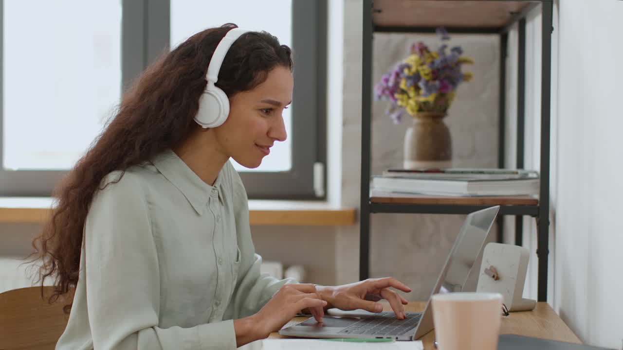 Woman working from home on a laptop with headphones