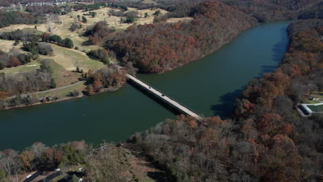 aerial view of bridge above curvy lake in warriors state park, tennessee usa on sunny fall day, drone shot