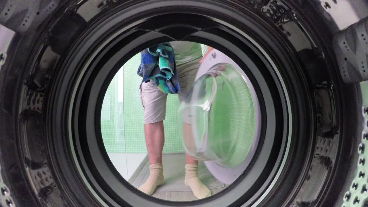 Mann legt Handtuch in Waschmaschine