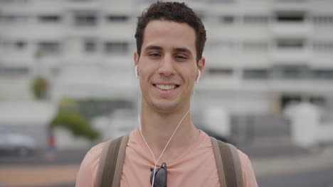 retrato jovem atrativo homem hispânico estudante sorrindo gostando de ouvir música usando fones de ouvido na cidade