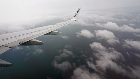 wing and winglet of ryanair airliner in flight against sky with clouds