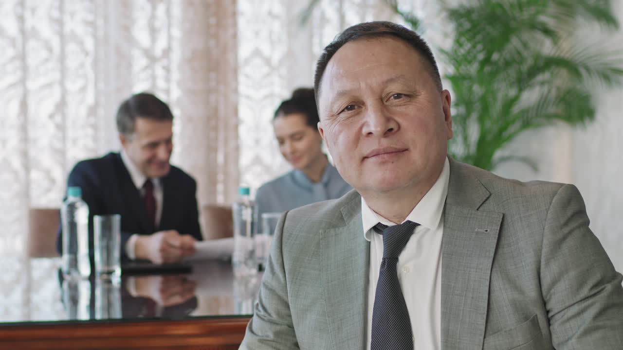 Portrait Of Smiling Asian Business Man At Conference Table