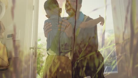 Animation-of-happy-african-american-father-and-son-embracing-over-grass