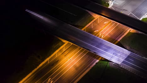 hyper lapse drone of intersection at night while cars drive onto the overpass