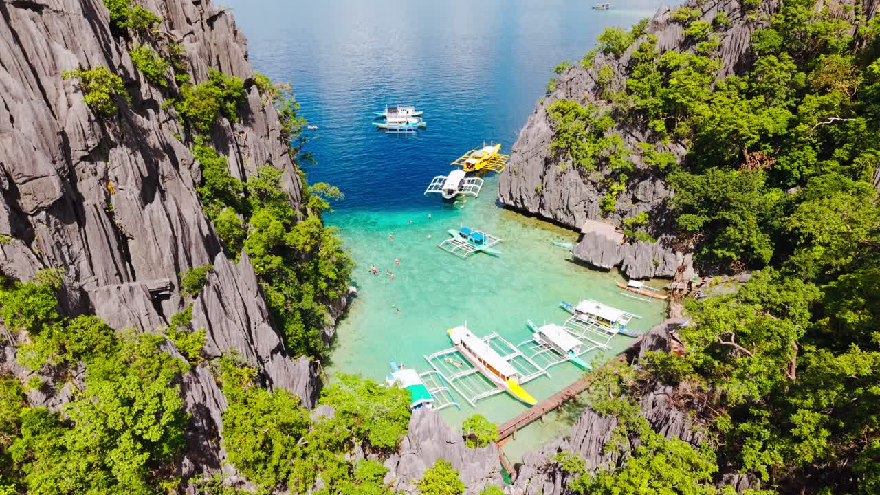 Laguna toska cerah, tebing kapur, perahu wisata di Barracuda Wall Coron
