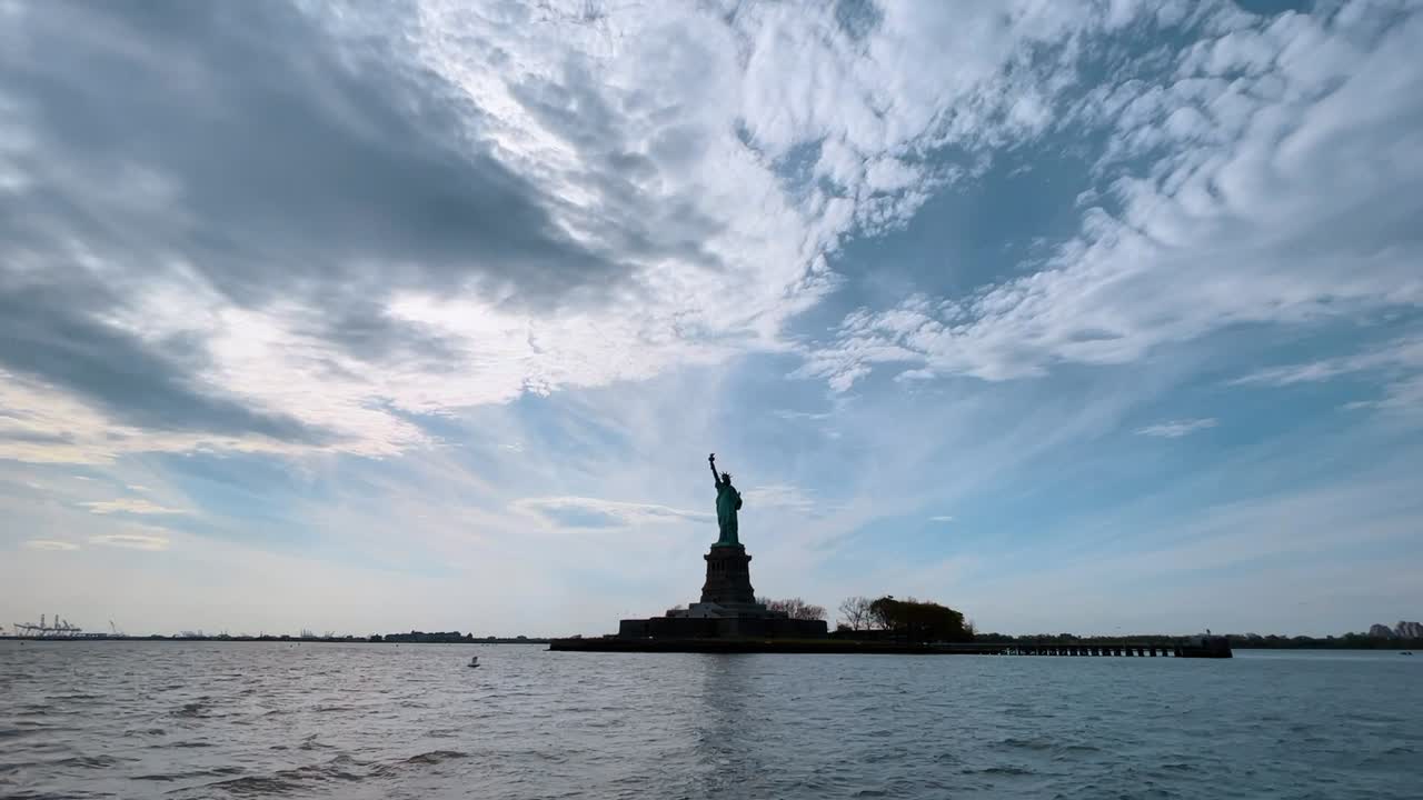 New York, USA, 8. srpna 2025: Silueta Sochy svobody pod zataženou oblohou. Silueta památníku Sochy svobody na ostrově Liberty Island, pohled z přístavní vody