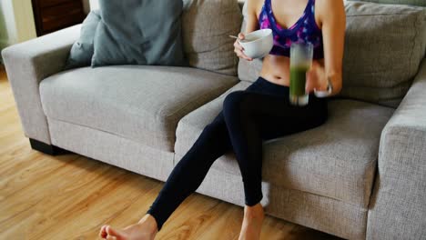 mujer en forma tomando el desayuno en la sala de estar
