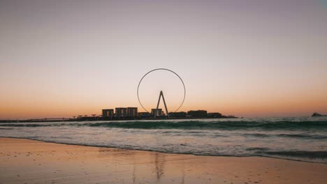 puesta de sol sobre el muelle de la rueda de la fortuna, olas de la costa, puerto deportivo de dubai