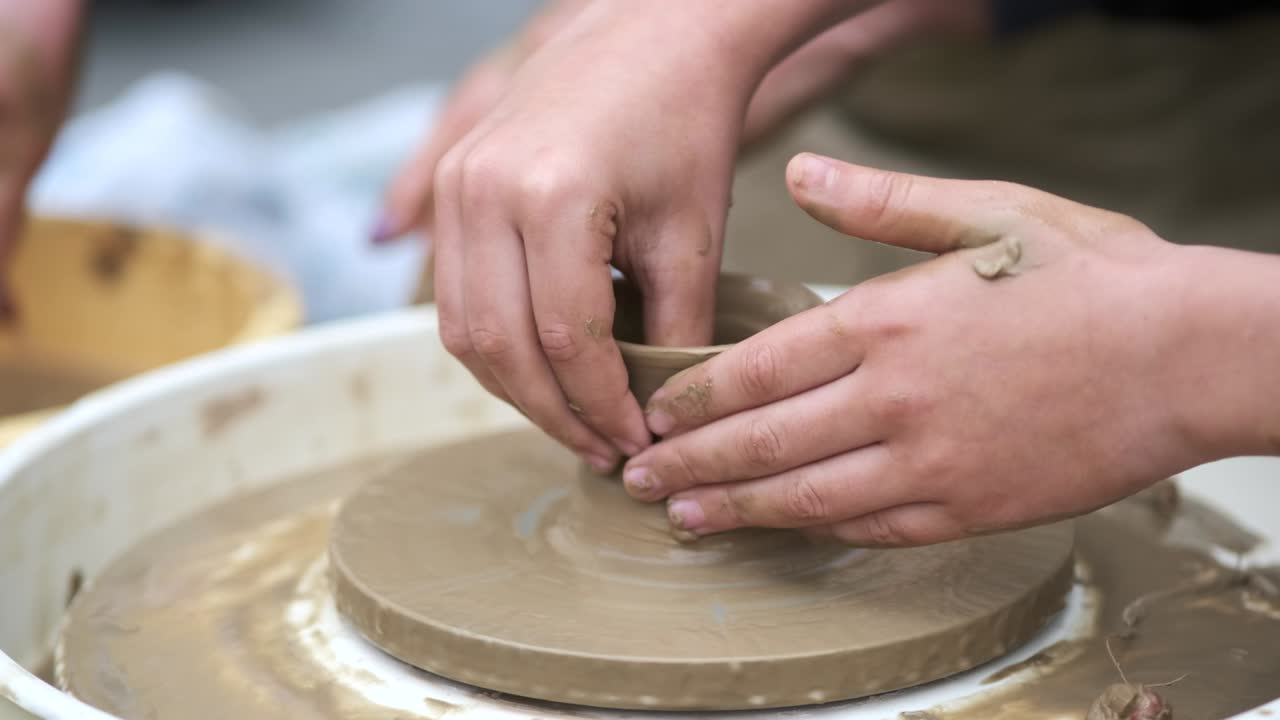 소년의 손이 도자기의 바에 점토 접시를 조각하는 클로즈업 도자기 훈련