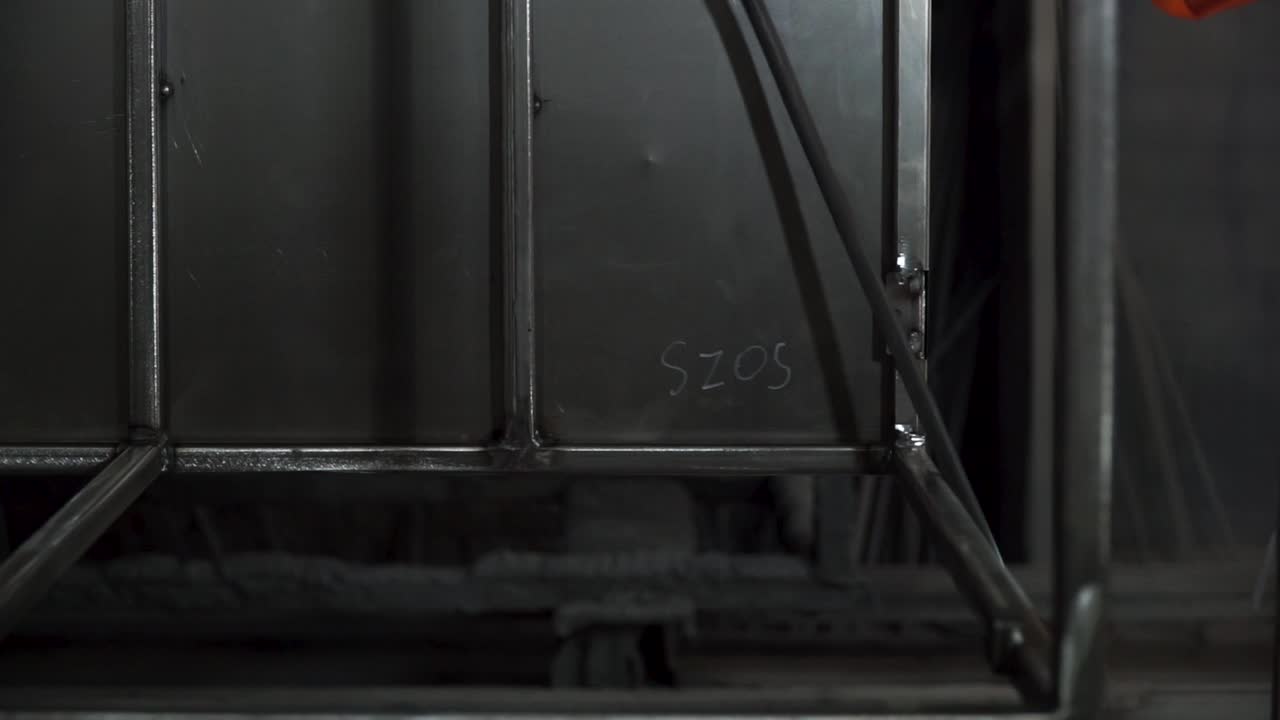 trabajador que utiliza una herramienta neumática en un marco metálico