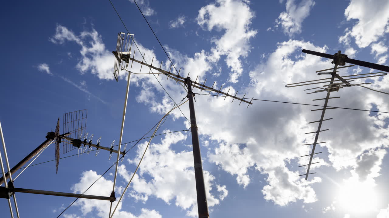A timelapse of the sky and clouds with television aerials in the foreground
