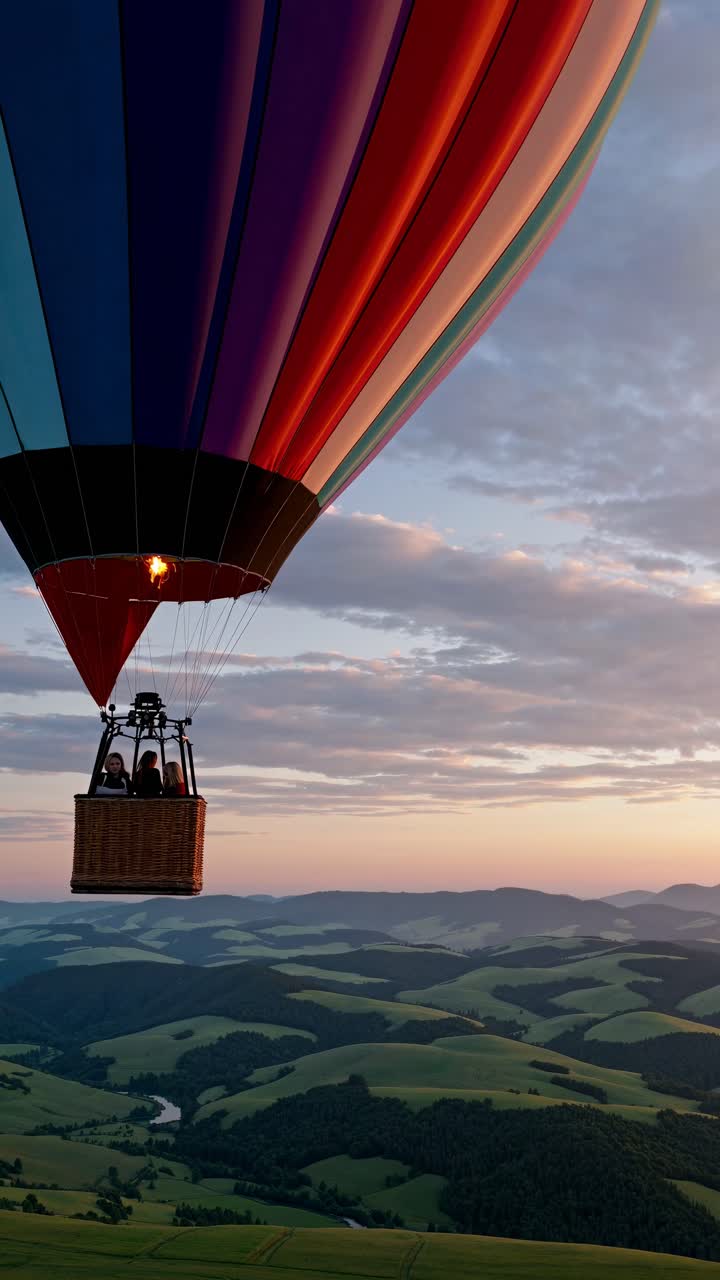 Aerial video shot of a colorful hot air balloon floating over rolling hills at sunset