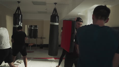 el equipo de taekwondo entrena artes marciales en el gimnasio de lucha. estudiantes de artes marciales hacen ejercicios en grupo haciendo golpes en el club deportivo en cámara lenta. entrenamiento de maestros de combate