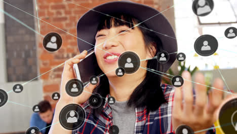 Animation-of-network-of-connections-with-icons-over-asian-woman-talking-on-smartphone