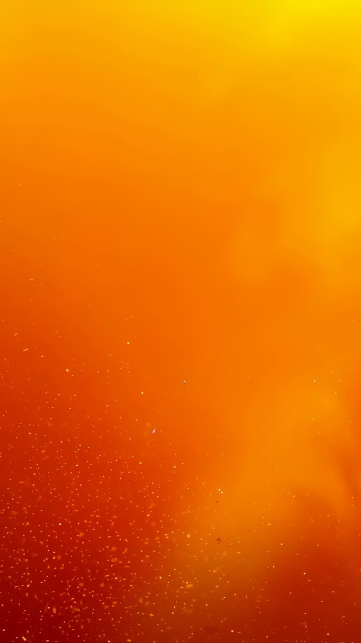Vertical video: Drifting glowing haze particles shifting orange gradient hues on screen, copy space