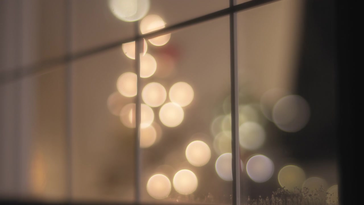 Close up of a window with Christmas decor inside, falling snow in winter