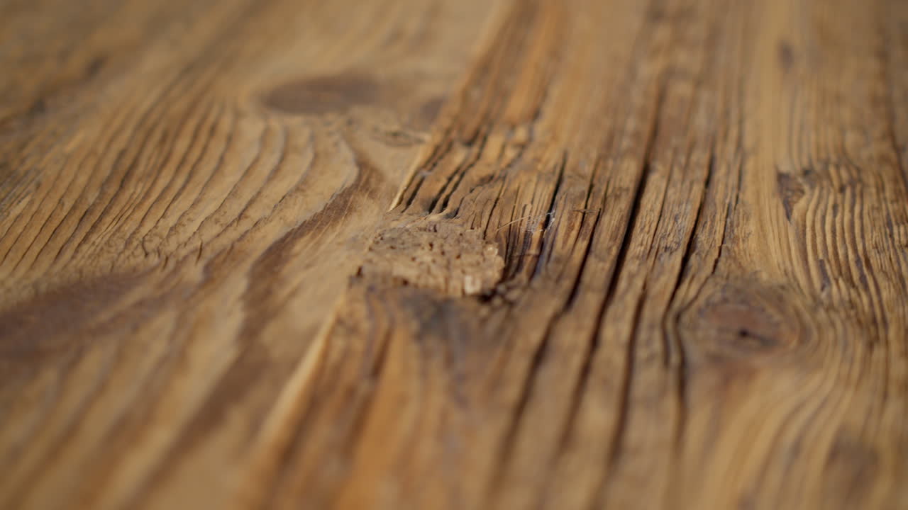 High quality video showing close up wooden surface with rich grain warm light and subtle texture captured in slow motion for a natural detailed and calm atmosphere