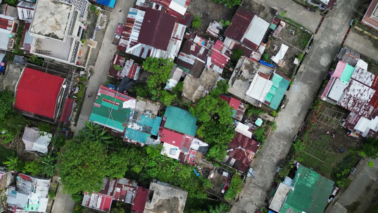 Aerial top-down view of quaint barangay village Sto. Domingo, Virac with dilapidated rooftops and trees at Catanduanes, Philippines