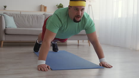 hombre con sobrepeso haciendo flexiones en casa