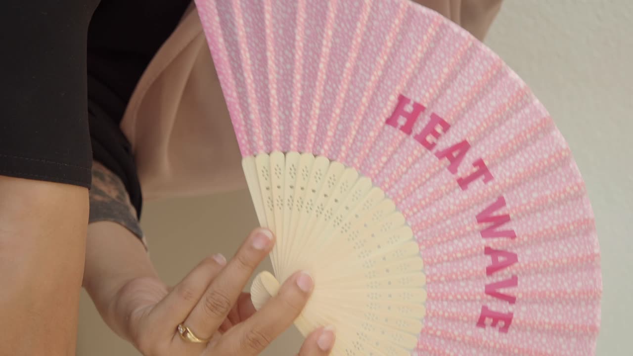 Person holding a fan with the words heat wave on it