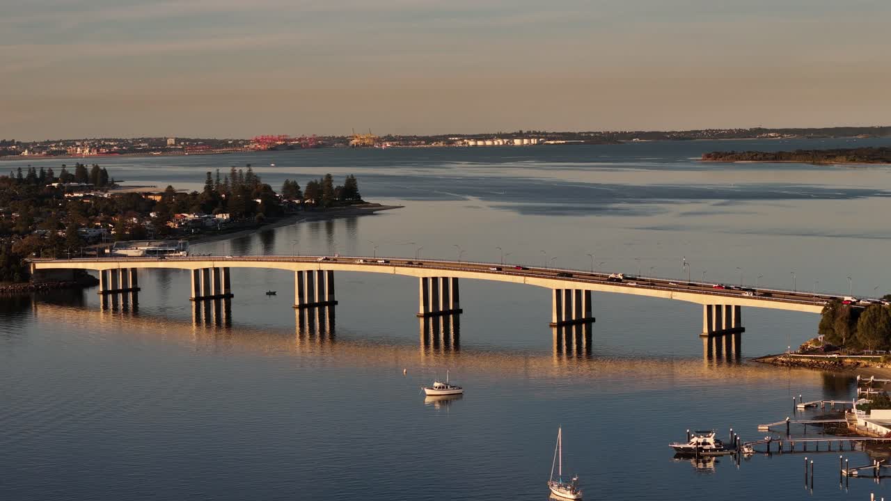 Aerial telephoto orbit of Captain Cook Bridge bathed in golden light over the Georges River, Sydney NSW Australia