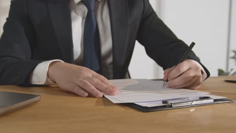 close up of businessman in office reviewing and making notes on application or cv for job vacancy