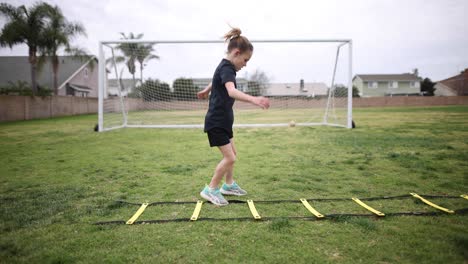 a young athletic girl does the ickey shuffle on a speed ladder as part of her warm up before practice