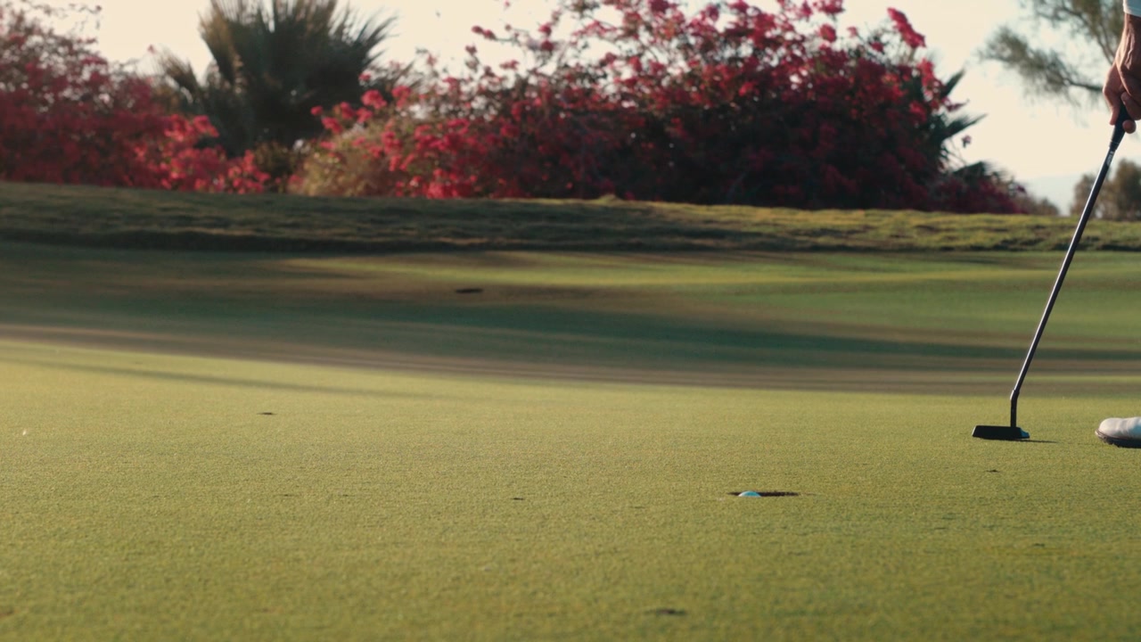Golfista esegue un putt da destra a sinistra sul green nella calda luce del tramonto, ripreso da vicino al rallentatore, ben adatto per il branding del golf, contenuti didattici e pubblicità sportive