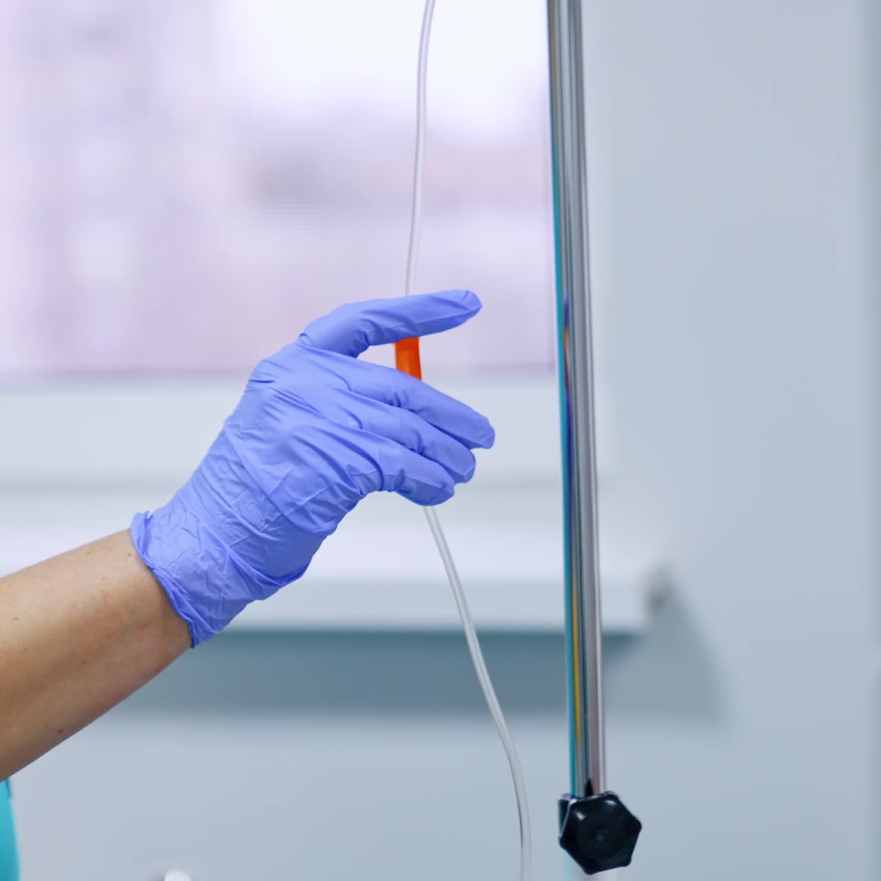 Operatore sanitario sconosciuto con guanti in lattice blu imposta il contagocce. Infermiera vicino all'apparecchiatura nel reparto ospedaliero