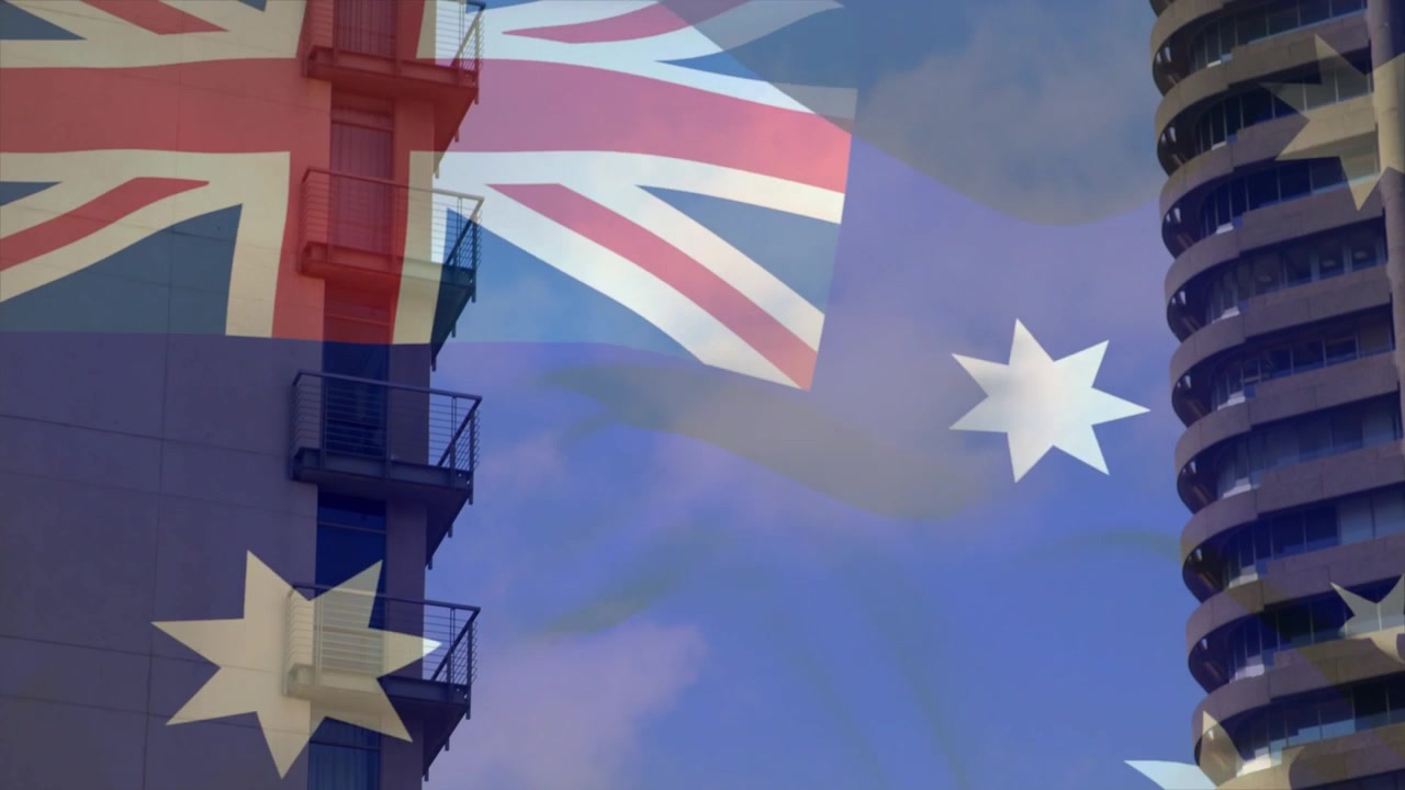 Viento suave empujando una fina bandera australiana ondeando en el horizonte, revelando y superponiéndose a las torres
