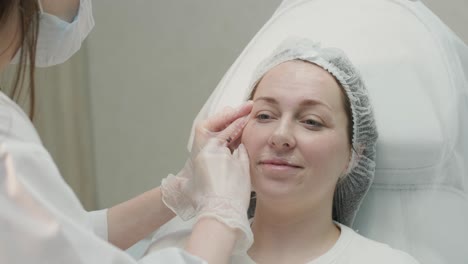 woman undergoing facial treatment at cosmetologist clinic